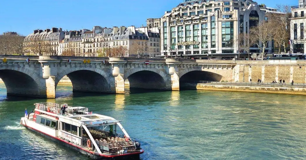 A Canauxrama boat cruises under Pont Neuf during a Seine River Canal tour in Paris.
