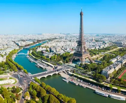 Aerial view of the Eiffel Tower and Seine River winding through central Paris on a clear day