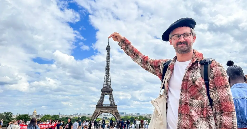 Tourist playfully posing near the Eiffel Tower at Trocadéro before a Seine River Cruise in Paris.
