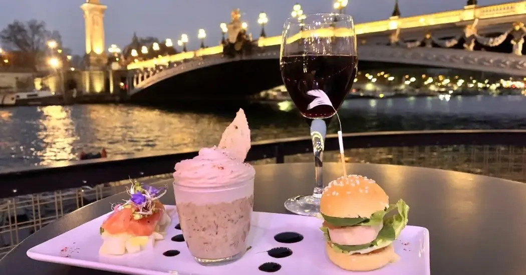 Luxurious dining by Seine River with city bridge backdrop.