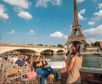 Tour guide narrating to tourists on a Seine River cruise with the Eiffel Tower in the background