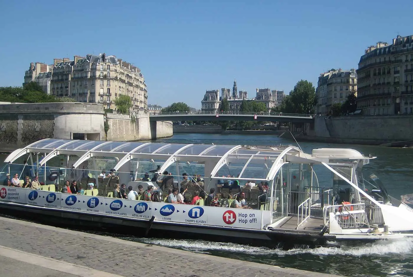 Hop-on hop-off Seine River boat cruising past historic buildings Hop-on hop-off Seine River boat cruising past historic buildings