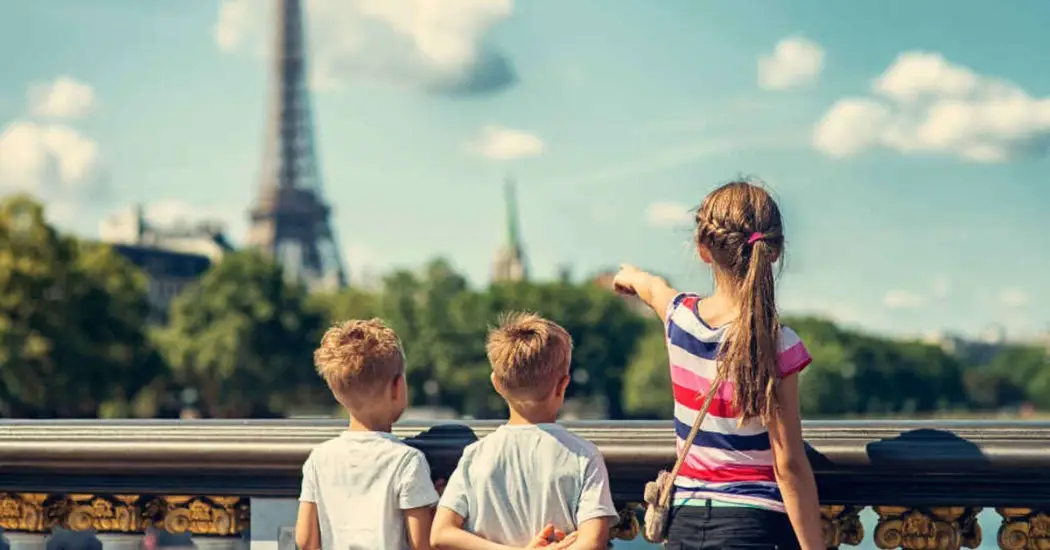 Children looking at the Eiffel Tower from a bridge near the Seine River during a family-friendly Paris cruise outing.