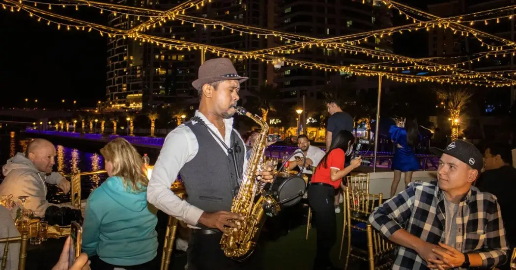 Live saxophone performance during rooftop dinner cruise with lights.