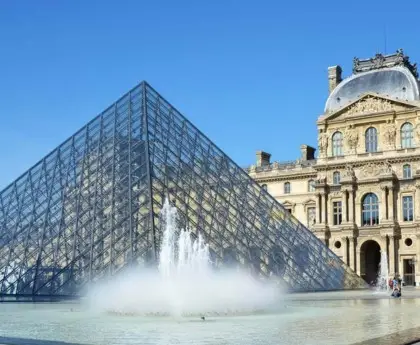 The glass Louvre Pyramid and water fountain in front of the historic Louvre Museum in Paris