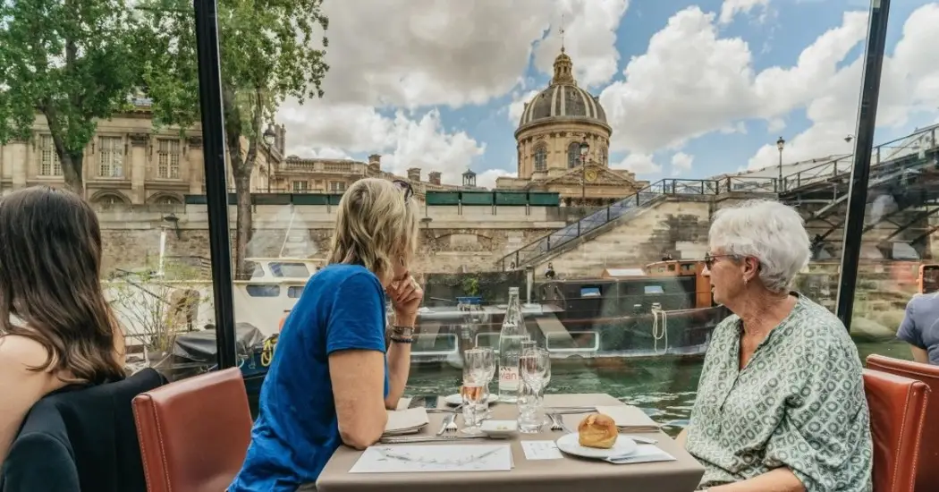 Daytime Seine River boat dining beside Parisian landmark architecture.