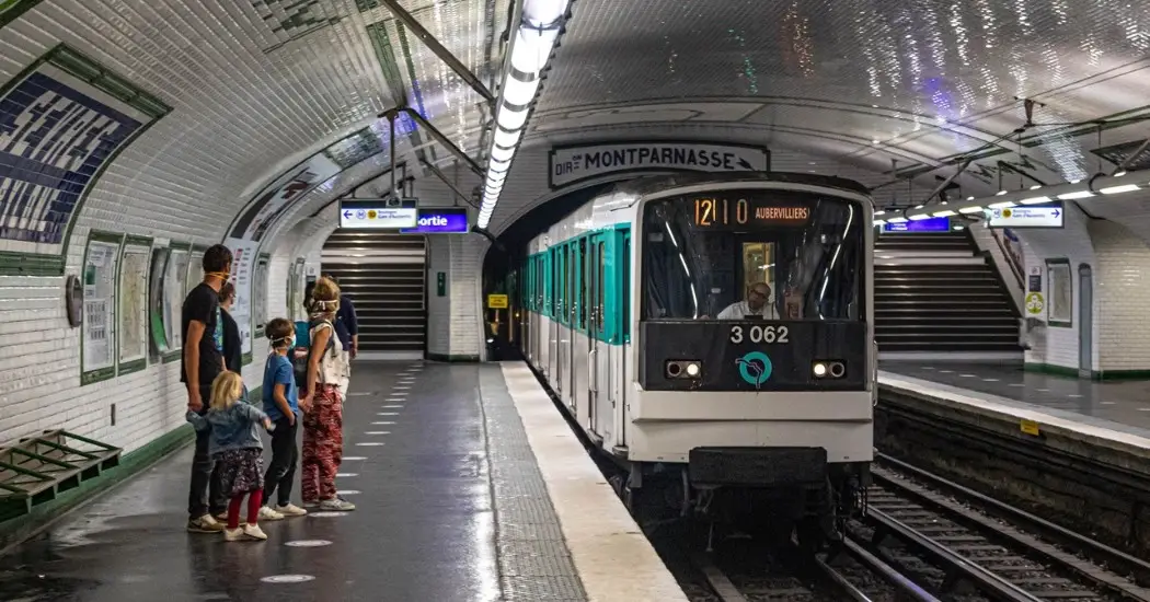 Paris Metro train arrives at Montparnasse station with passengers waiting.