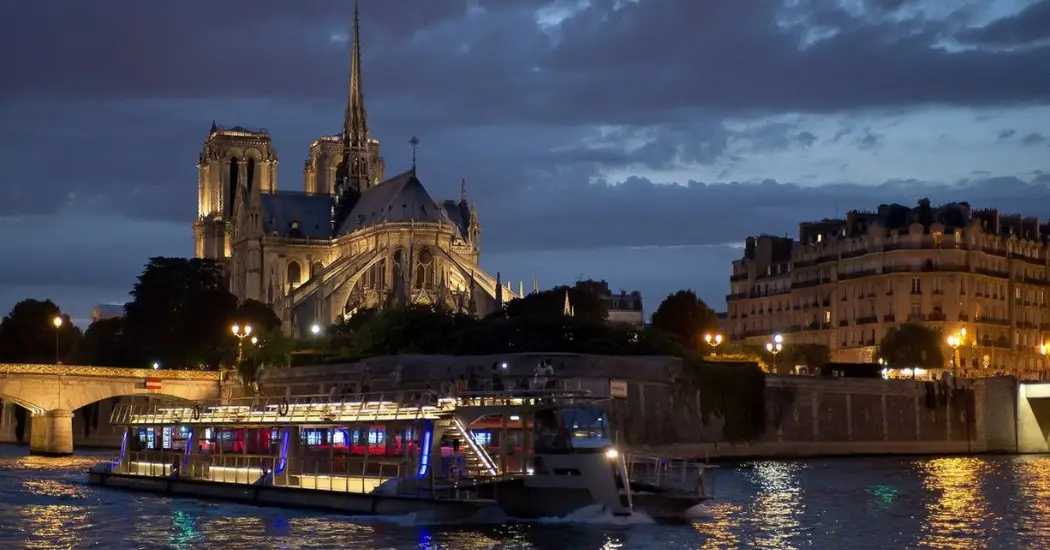 Seine River night cruise passing Notre-Dame Cathedral in Paris.