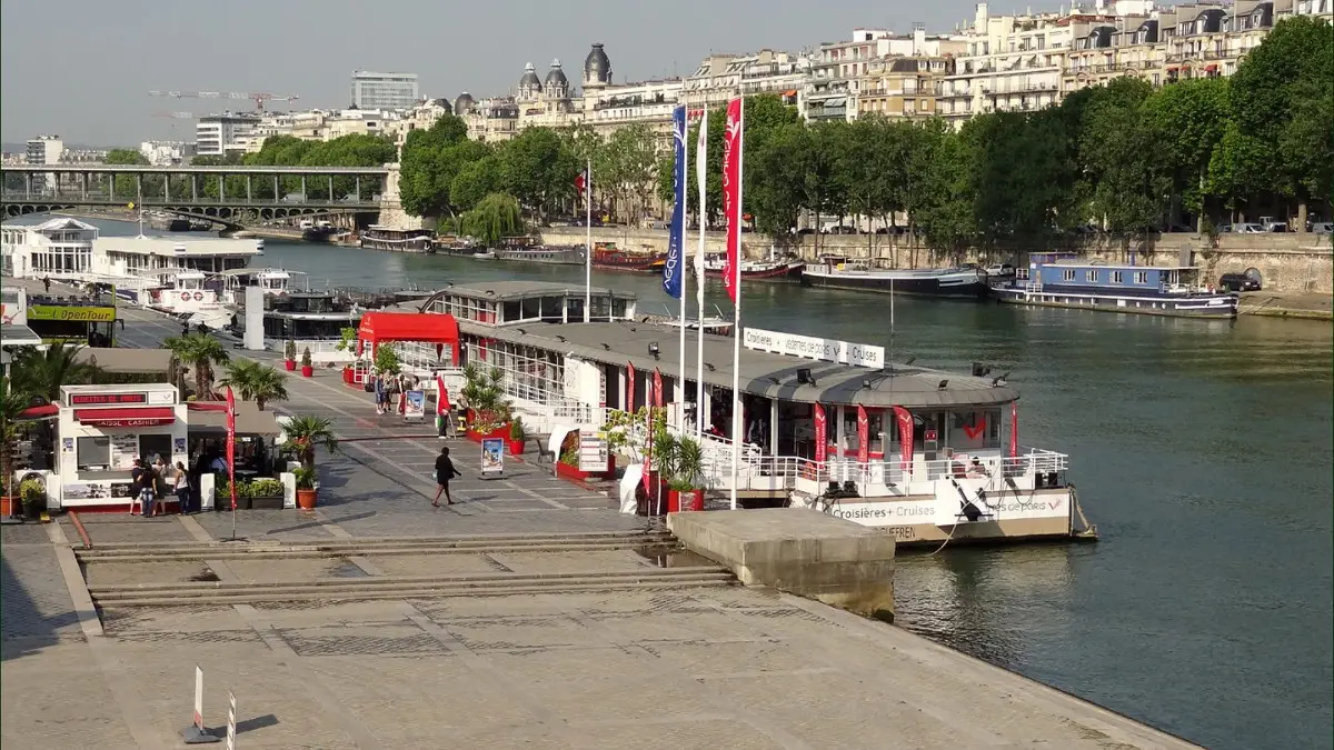 Seine River cruise departure point in Paris with docked boats.