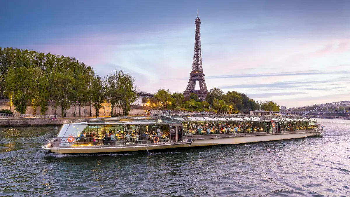 Glass-roof dinner cruise boat sailing on the Seine River near the Eiffel Tower