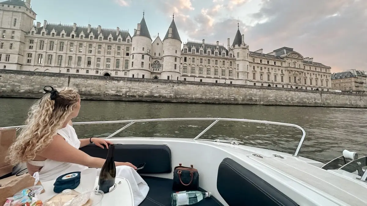 Woman enjoying peaceful Seine River private cruise with Paris landmarks in view.
