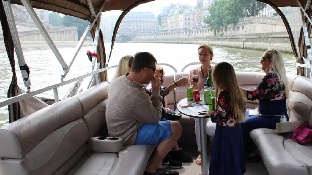 A family enjoying a private Seine River cruise in Paris with drinks and relaxed seating