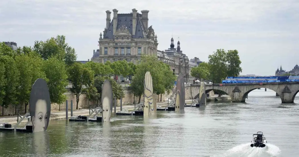 Public art display in Seine River near iconic Paris landmarks.

