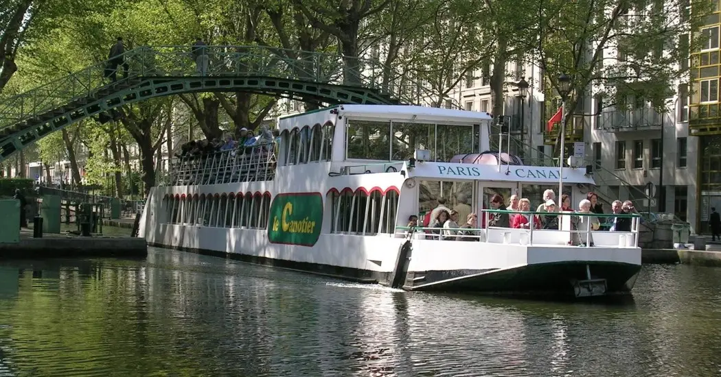 A scenic Canal Saint-Martin cruise in Paris with tourists viewing city landmarks and canal locks.