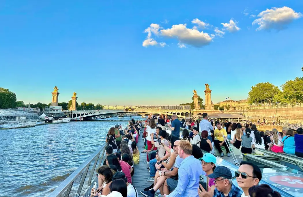 Tourists enjoying a scenic Seine River cruise near Pont Alexandre III in Paris