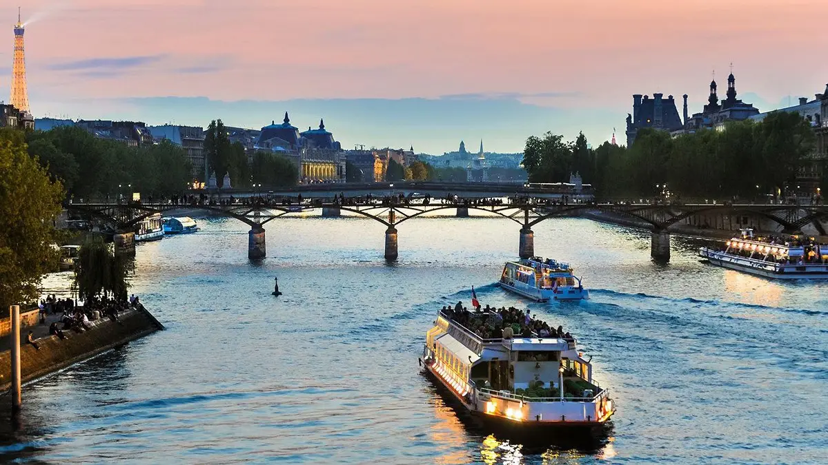 Seine River cruise boats at sunset with Eiffel Tower glowing.