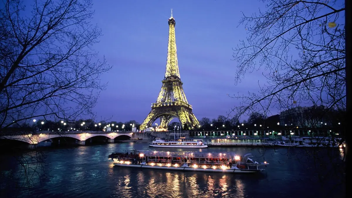 Seine cruise passes Eiffel Tower glowing against Paris night sky. Seine cruise passes Eiffel Tower glowing against Paris night sky.