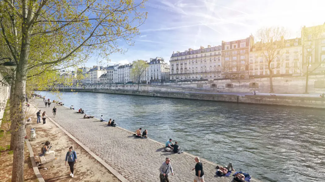 People relaxing, walking, and sunbathing along the scenic Seine River promenade in Paris