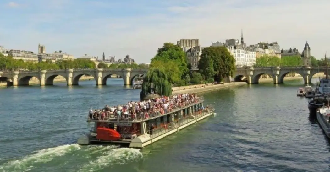 River cruise with full deck of tourists in Paris.
